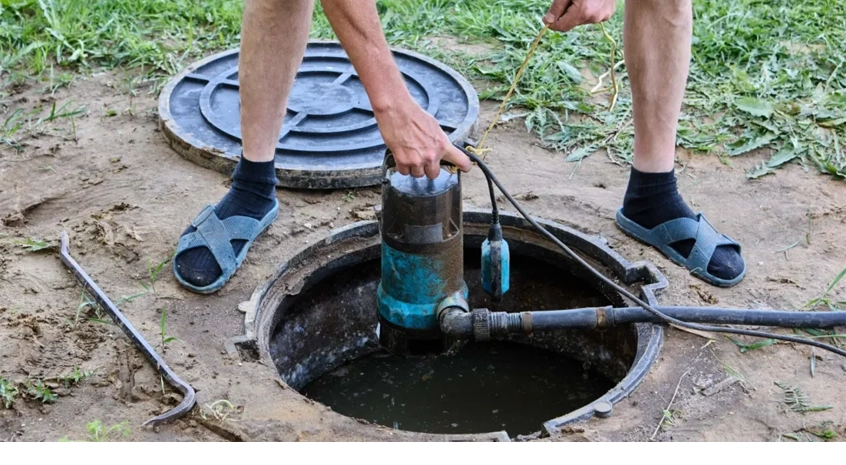 Technician monitoring septic pumping hose running from truck to underground tank