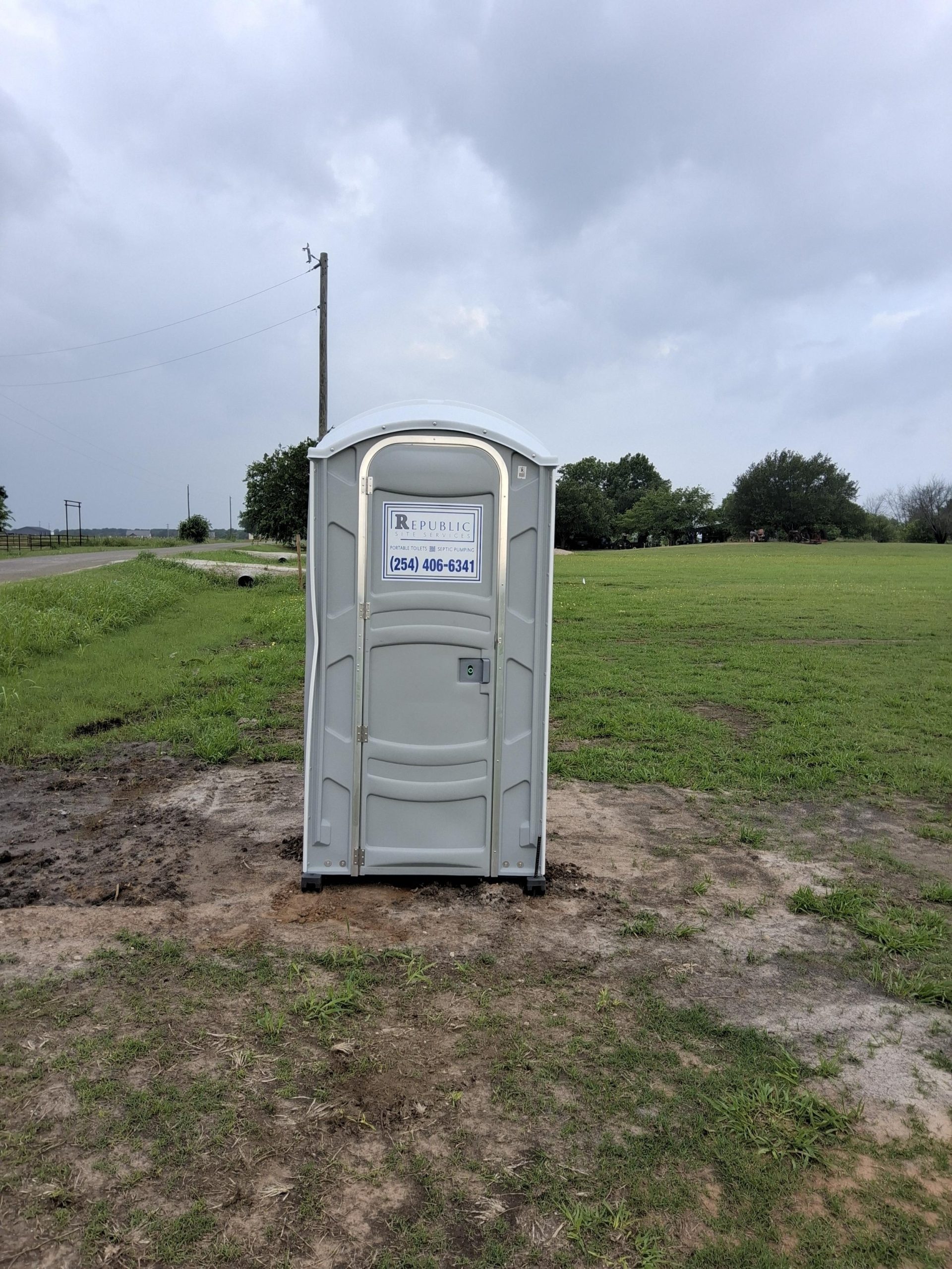 Portable Toilet on Grassy Field under Cloudy Sky
