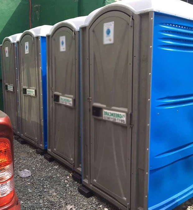 Row of Blue Portable Toilet Rentals on Gravel Surface