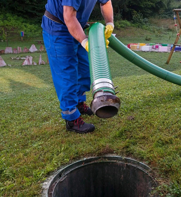 Worker Using Equipment for Septic Pumping Services on a Lawn