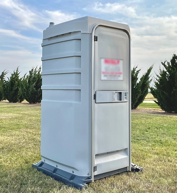 Gray Portable Restroom on Grass Field Under Cloudy Sky