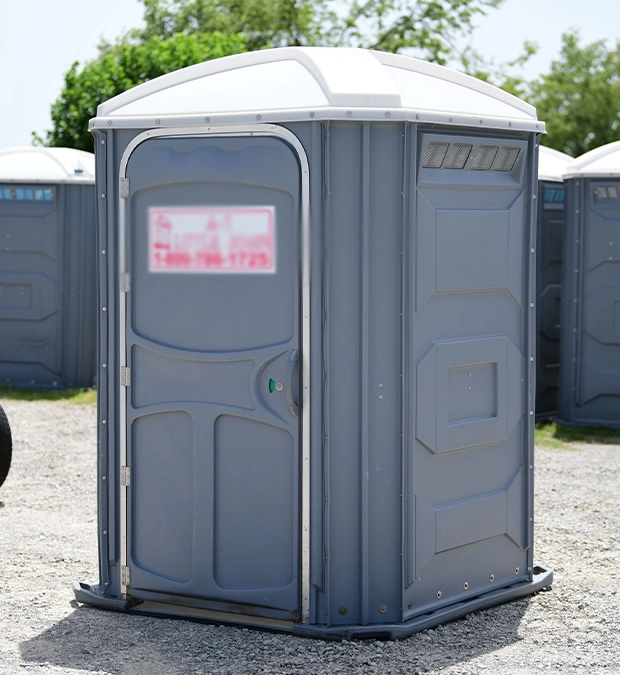 Gray Portable Toilet in an Outdoor Setting with Trees in Background