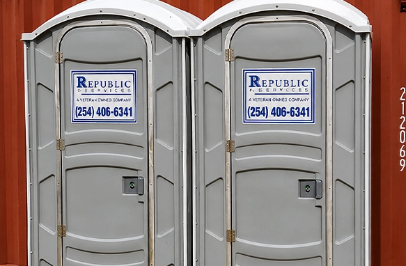 Two Outdoor Portable Toilets with Company Contact Information Displayed