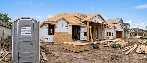 Construction Site with Portable Toilet Rental Next to Unfinished House