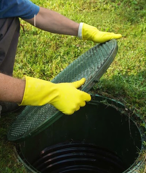 Person Lifting Septic Tank Lid with Yellow Gloves for Septic Services